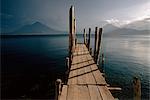 Wooden jetty and volcanoes in the distance, Lago Atitlan (Lake Atitlan), Guatemala, Central America