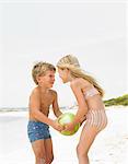 Jungen und Mädchen (6-8) am Strand spielen mit ball