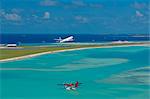 Passenger jet taking off from Male International Airport, and Maldivian air taxi ready to take off, Maldives, Indian Ocean, Asia