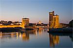 La Chaine and St. Nicholas towers at the entrance to the ancient port of La Rochelle at dusk, Charente-Maritime, France, Europe