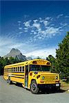 Yellow school bus, for students on geology field trip, Waterton Glacier International Peace Park, Rocky Mountains, Montana, United States of America, North America