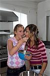 Teen girls taste cake dough