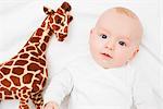Baby laying next to a plush giraffe