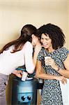 Two women gossiping by water cooler