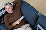 Man relaxing on sofa with tv remote