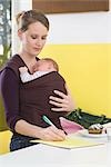 Mother with baby in baby sling,  writing
