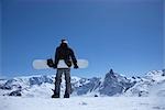 Man standing on mountain with snowboard
