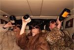 Three women drinking champagne in car