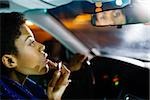 Woman putting on lipstick in car