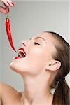 Woman holding a red chili pepper near her mouth