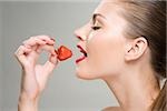 A woman eating a strawberry