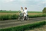 Deux vélos à travers la campagne, souriant à la caméra d'équitation