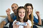 Girl playing video game, parents watching and cheering