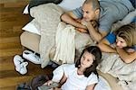 Family lying in bed watching television, directly above