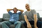 Two men sitting on sofa, laughing