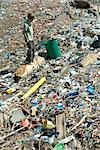 Boy standing in garbage dump, garbage can nearby, high angle view