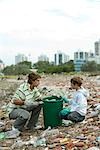 Young male and boy picking up recyclable materials in garbage heap