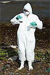 Person in protective suit holding up flasks filled with polluted water