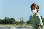 Boy standing outdoors, wearing pollution mask