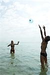 Teen friends waist deep in water playing with beach ball