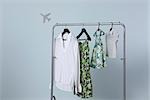 Family's summer clothing hanging on clothes rack, airplane shape in background