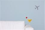 Cocktail on arm of sofa, airplane shape in background