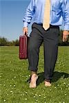 Homme d'affaires de marcher pieds nus sur l'herbe