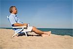 Homme de détente sur la plage avec une tasse de café, lac Michigan, USA