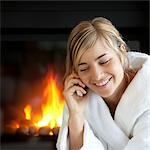 Woman Sitting by the Fireplace, Talking on Cell Phone