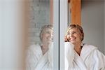 Woman in Bathrobe Talking on Cell Phone and Looking Out the Window