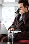 Mann im Bademantel Laptopcomputer verwenden und eine Tasse Kaffee trinken