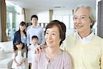 Senior couple standing together with his family in backgroud