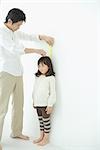 Father measuring daughter height on wall