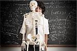 Boy and skeleton in front of blackboard