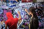 Un jeune homme et une femme graffiti de pulvérisation