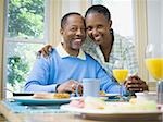 Portrait d'une femme et un homme souriant à la table du petit déjeuner