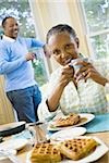 Portrait of a senior woman sitting at the breakfast table with a senior man standing behind her