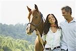 Portrait of a man and a  woman standing with a horse