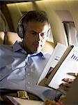 A senior man reading a magazine in an airplane