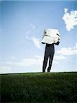 Businessman standing on the grass and reading a newspaper