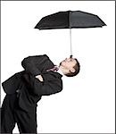 Businessman balancing umbrella on his forehead