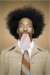 Man with an afro in beige suit blowing a bubble