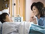 Older woman in hospital holding hands with woman smiling