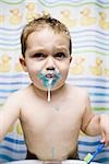 Young boy brushing teeth in bathroom sink