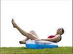 Woman in bikini lying in swimming ring on grass smiling