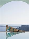 Woman reclining by infinity pool outdoors