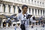 Woman in public square with pigeons smiling