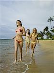 Three teenage girls running on the beach