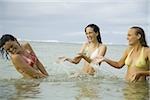 Three teenage girls splashing water in the sea