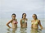 Three teenage girls standing in the sea and laughing